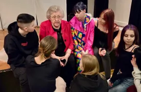 Młodzież siedzi obok starszej pani i słucha