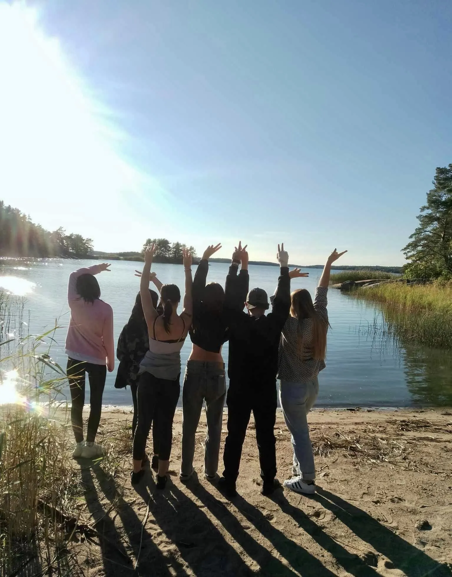 Młodzież stoi nad brzegiem jeziora