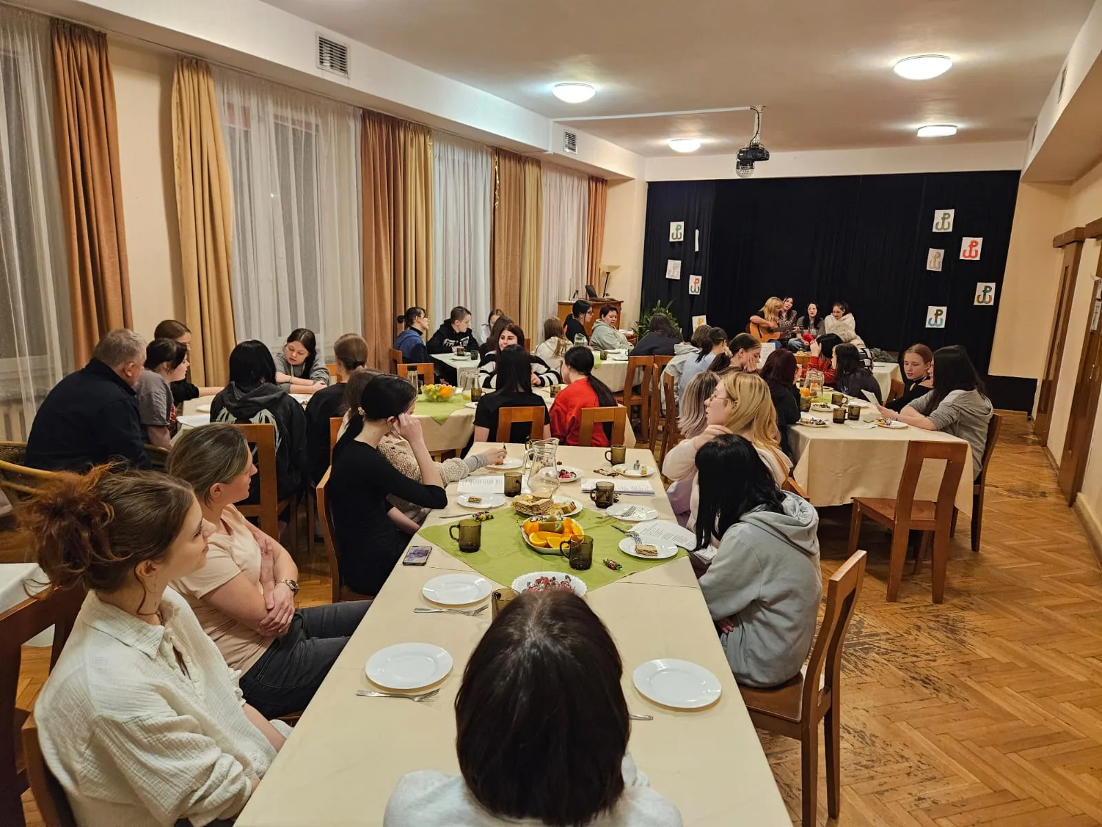 Młodzież siedzi przy stołach