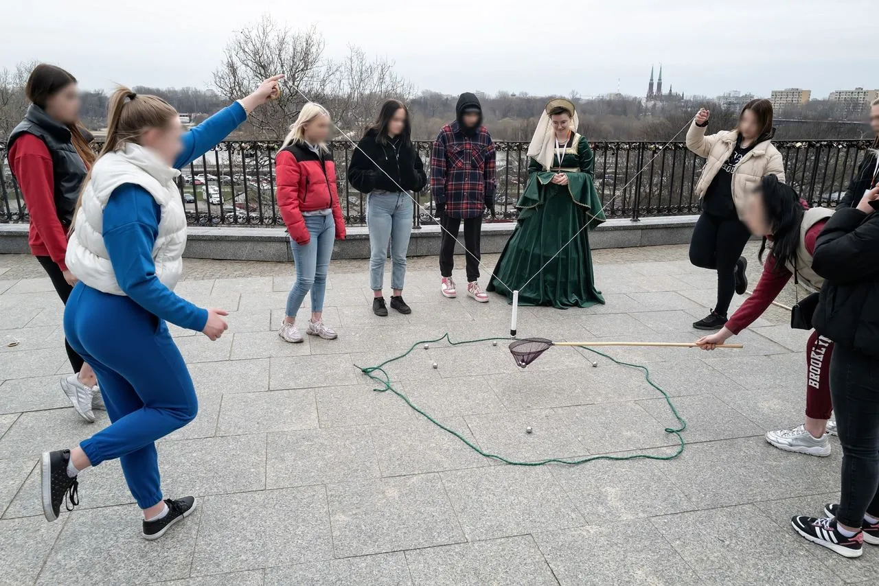 Osoby biorą udział w grze miejskiej