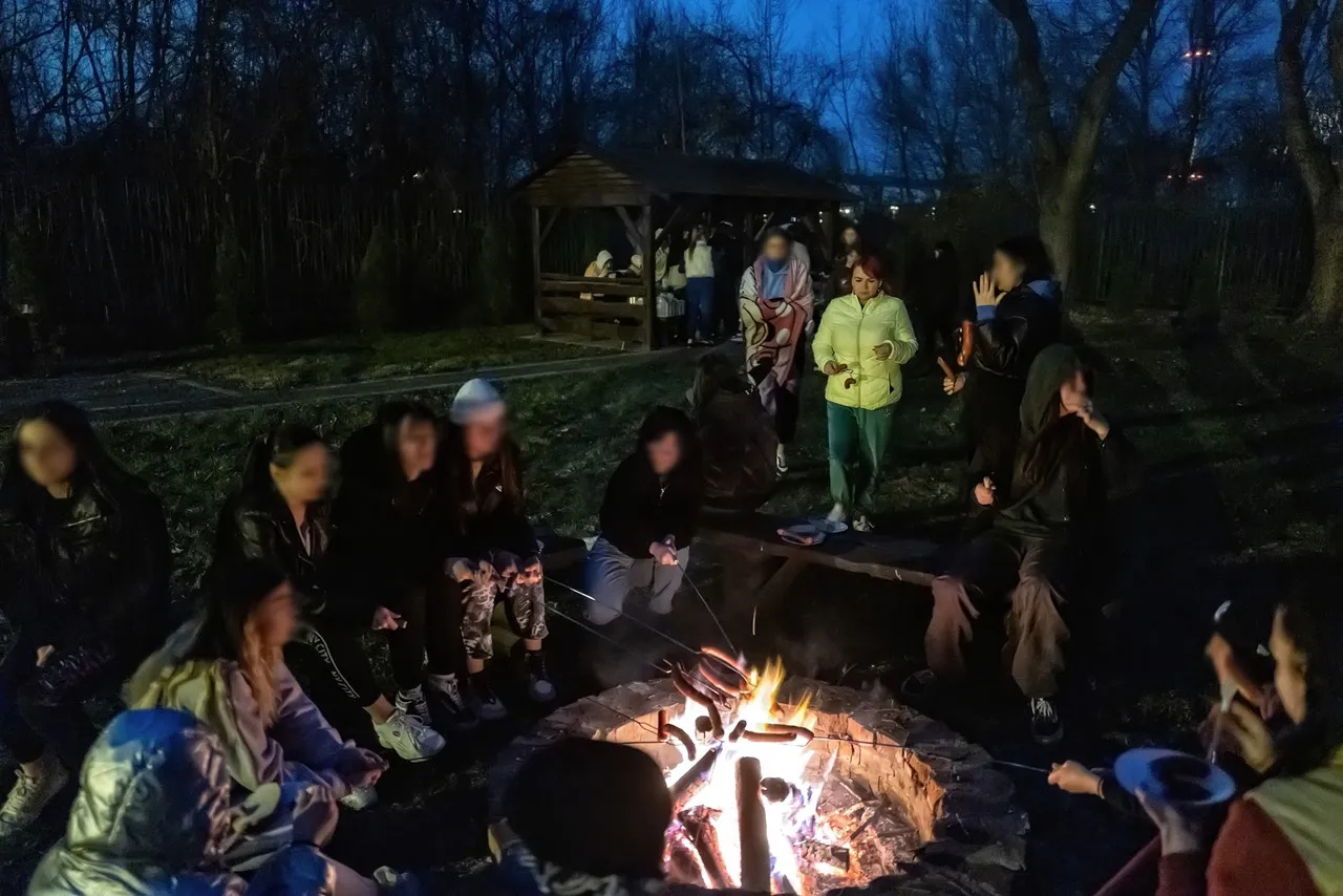 Osoby siedzą wokół ogniska